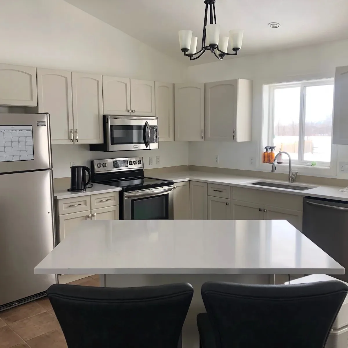Beautiful kitchen cabinets refinished in Benjamin Moore Edgecomb Gray and Simply White with white quartz island by TAG Painting