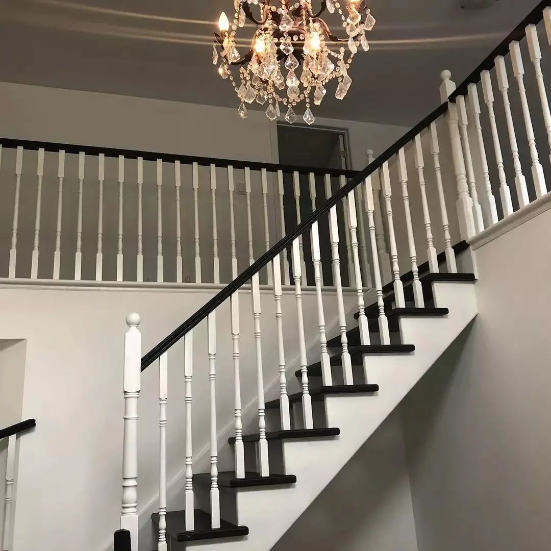 Stately staircase showing crisp white painted spindles, dark stained treads, and a gorgeous hanging chandelier refurbished by TAG Painting